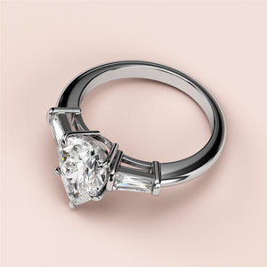 Elegant white gold butterfly pear three-stone engagement ring with tapered baguette diamonds for a timeless look.
