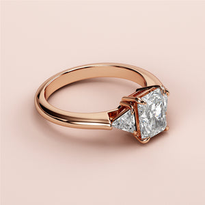 "Elegant 14K rose gold engagement ring with radiant-cut diamond and two triangular side stones for timeless beauty."