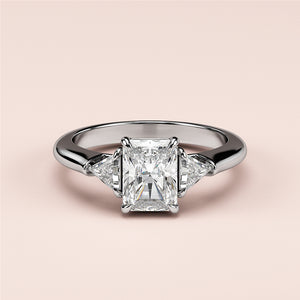 Elegant three-stone diamond engagement ring in 14K white gold, featuring a radiant cut center and trapezoid side diamonds.