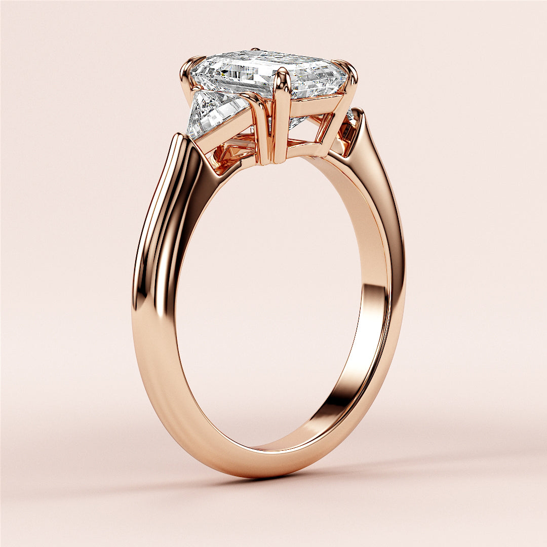 Elegant 14K rose gold engagement ring with emerald three-stone triangle design, showcasing a stunning marquise-cut diamond.