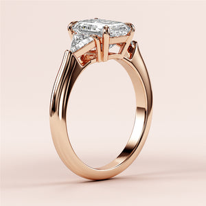 Elegant 14K rose gold engagement ring with emerald three-stone triangle design, showcasing a stunning marquise-cut diamond.