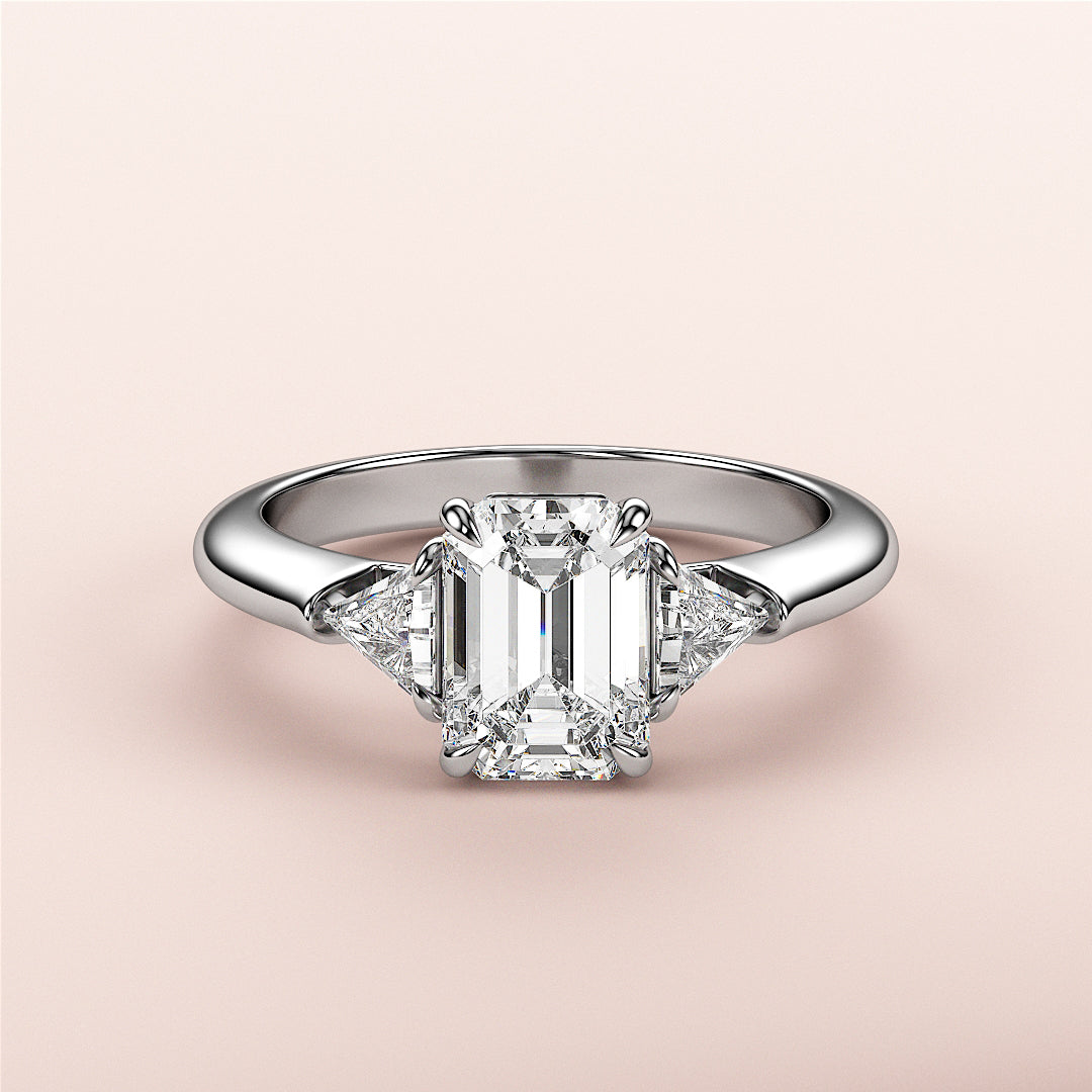 Elegant emerald-cut diamond engagement ring with two trillion-cut diamonds in 14K or 18K gold or platinum. Perfect for special occasions.