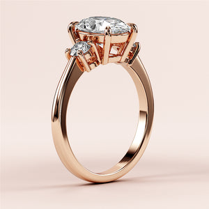 Beautiful rose gold engagement ring featuring an oval-cut diamond and two round accent diamonds, crafted in 14K or 18K gold and platinum.