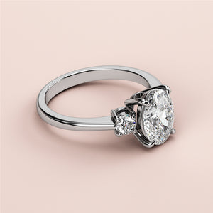 Elegant three-stone engagement ring with oval diamond in 14K white gold, featuring two round diamonds for added sparkle.