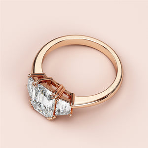 Elegant emerald cut diamond ring in rose gold, featuring a stunning three-stone design, available in 14K, 18K, or platinum.