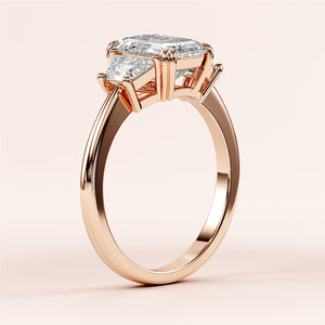 Elegant 14K rose gold engagement ring featuring a stunning prong-set emerald in a unique rectangular shape.