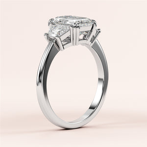 Elegant 14K or 18K white gold or platinum engagement ring with emerald three-stone trapezoid setting on a neutral background.