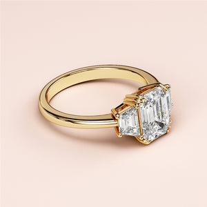 14K yellow gold engagement ring featuring a three-stone emerald and trapezoid cut, perfect for elegant occasions.