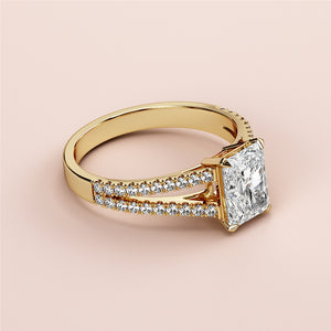 Radiant-cut diamond engagement ring in 14K or 18K gold with split shank pave diamonds, set on a light background.