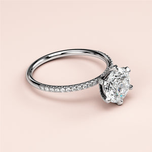 Elegant round solitaire engagement ring in white gold with pave accents, featuring a brilliant diamond and sparkling band options.