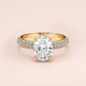 Elegant 14K yellow gold engagement ring with oval diamond and pave accents on a soft pink background. Perfect for special moments.