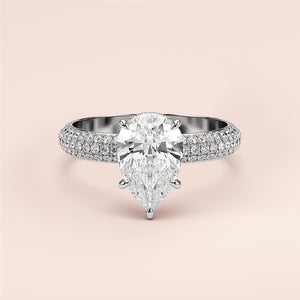 Elegant pear-shaped diamond engagement ring in 14K or 18K gold or platinum, adorned with smaller diamonds on a blush background.
