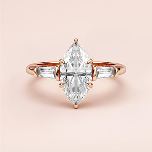 Elegant marquise diamond engagement ring with tapered baguette diamonds in 14K/18K gold or platinum on a soft pink background.