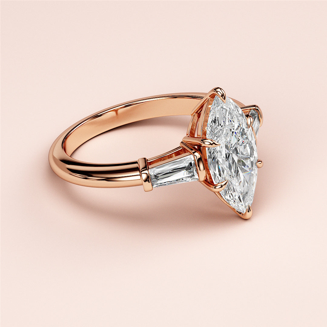 Rose gold engagement ring with marquise-cut diamond and tapered baguette side stones, available in 14K, 18K, and platinum.