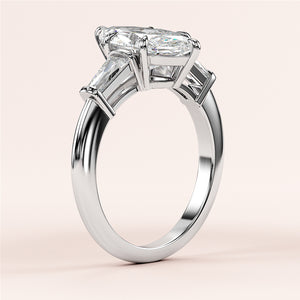 Elegant three-stone engagement ring in 14K/18K white gold, featuring a radiant-cut center diamond and trapezoid-cut side stones.