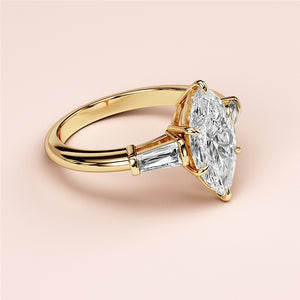 Exquisite 14K or 18K gold engagement ring featuring a marquise diamond and tapered baguette side stones on a smooth band.