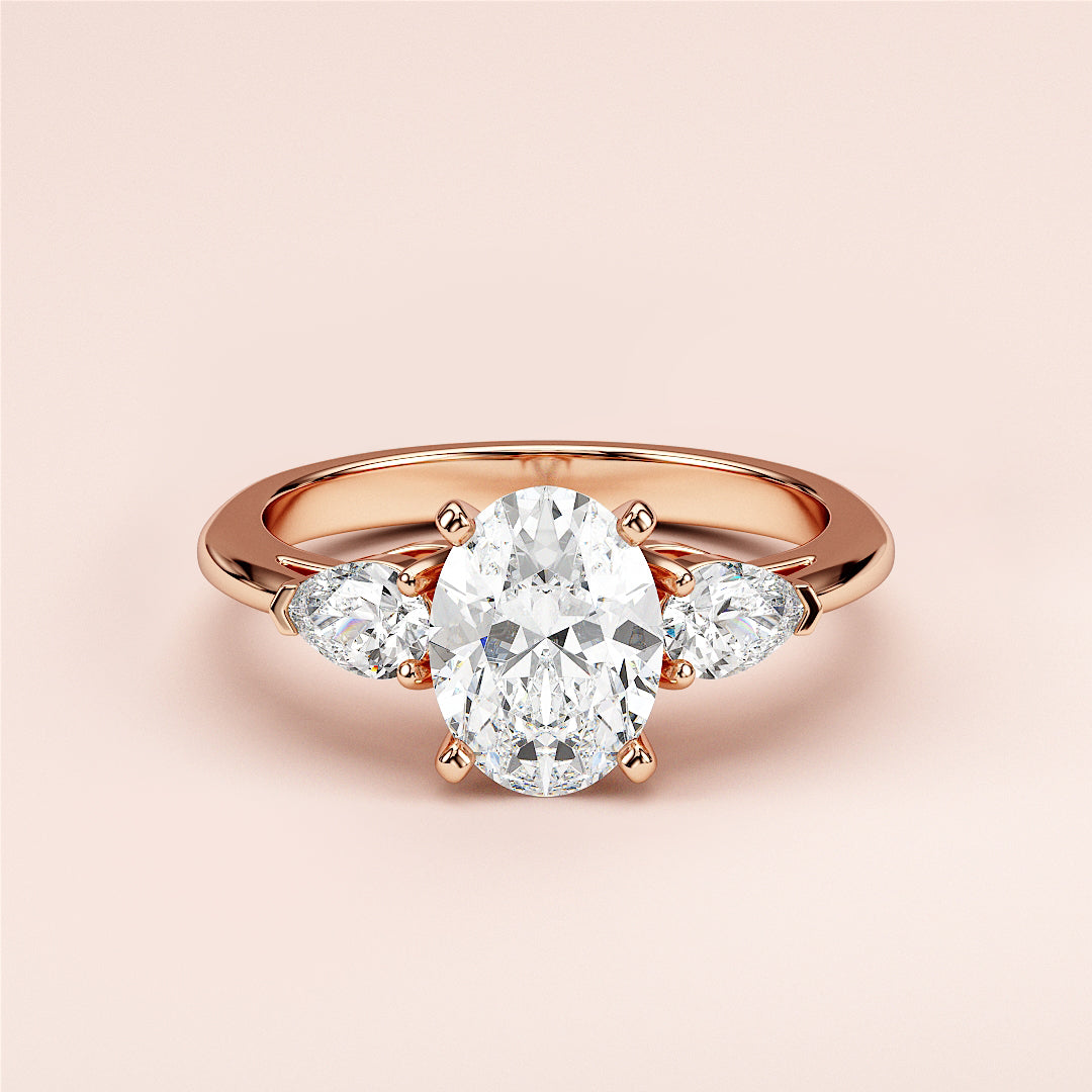Stunning 14K or 18K rose gold oval three-stone engagement ring with a diamond centerpiece and pear-shaped diamonds.