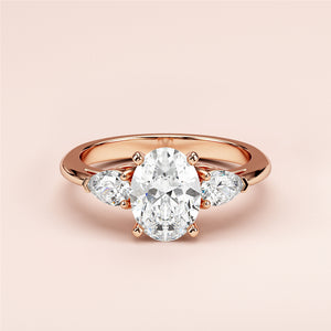 Stunning 14K or 18K rose gold oval three-stone engagement ring with a diamond centerpiece and pear-shaped diamonds.