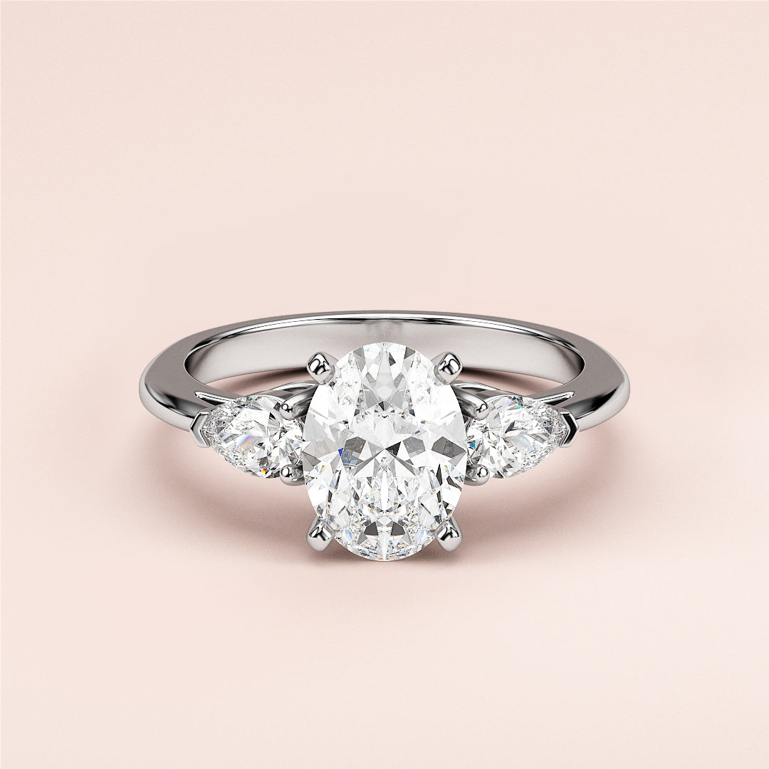 Elegant three-stone engagement ring with an oval diamond center and pear side stones in 14K/18K gold or platinum.