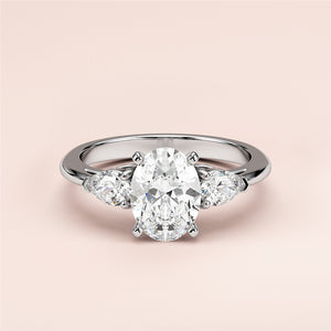 Elegant three-stone engagement ring with an oval diamond center and pear side stones in 14K/18K gold or platinum.