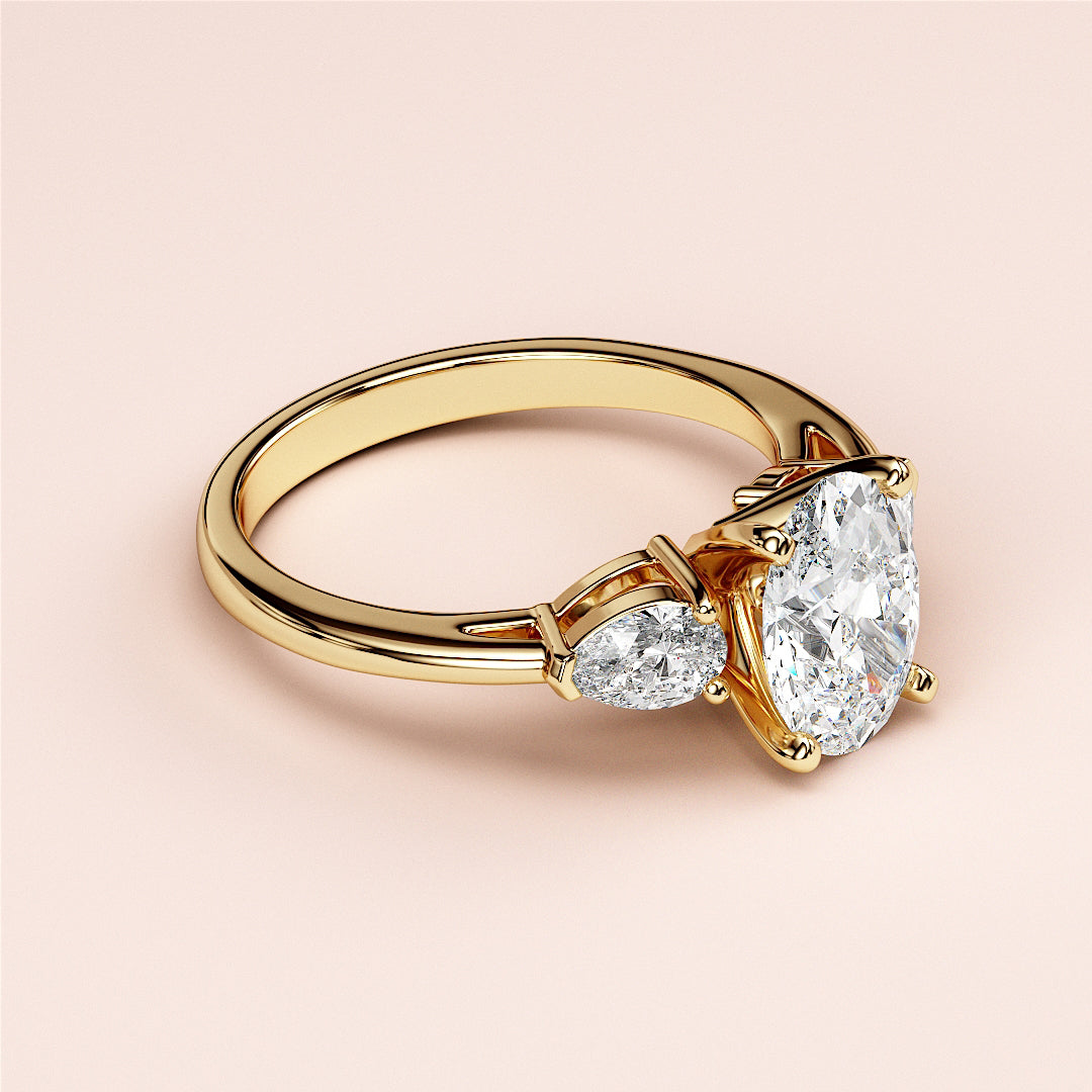 Elegant 14K yellow gold engagement ring featuring a pear-shaped diamond center flanked by two marquise-cut diamonds.