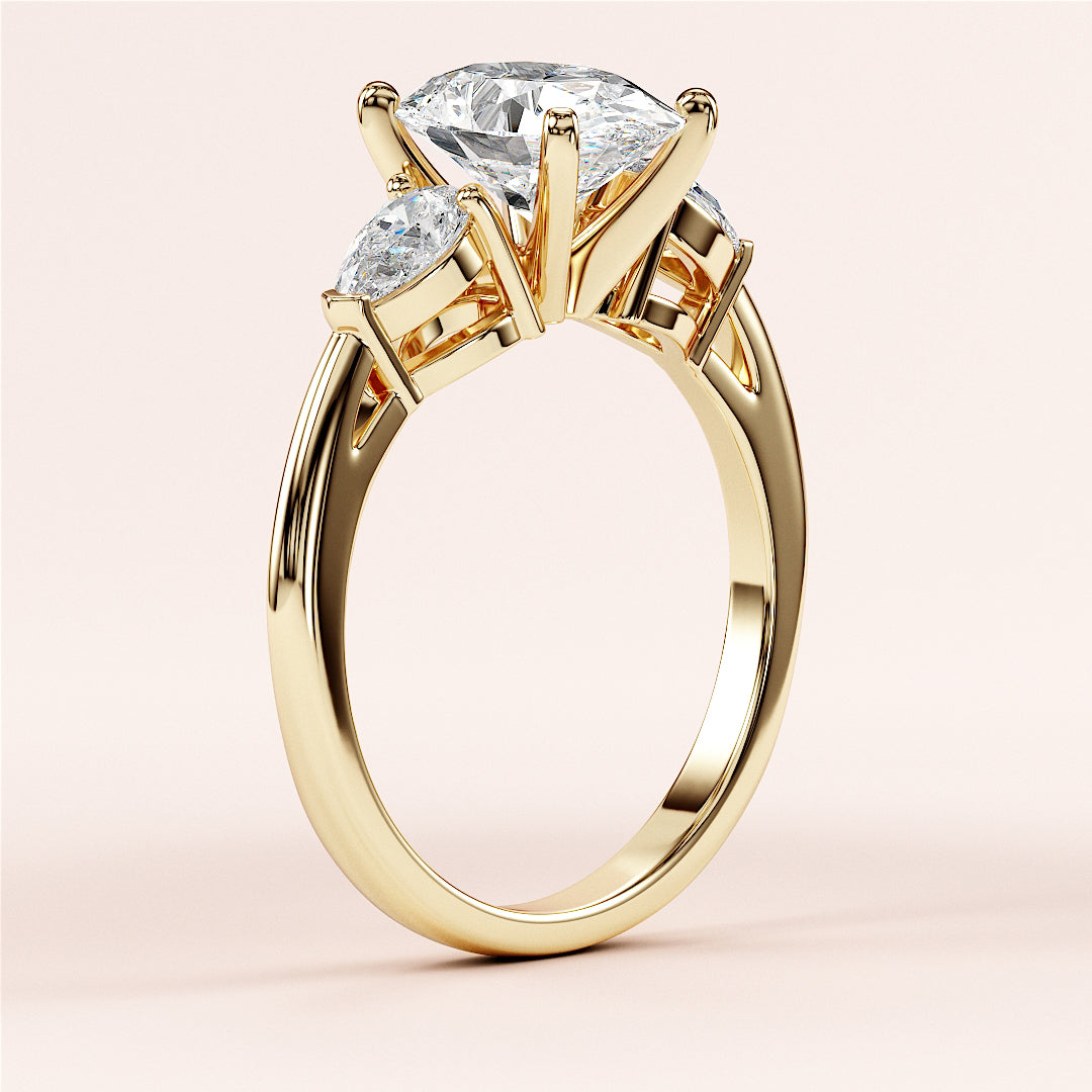 Elegant three-stone engagement ring in 14K yellow gold featuring a marquise-cut diamond and pear-shaped side stones.
