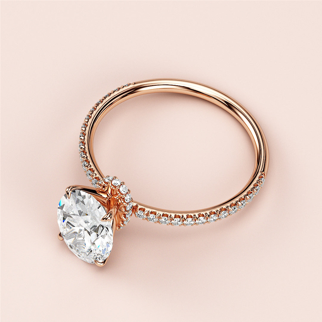 Elegant oval-shape diamond engagement ring in 14K or 18K rose gold with a sparkling pave band on a pink background.