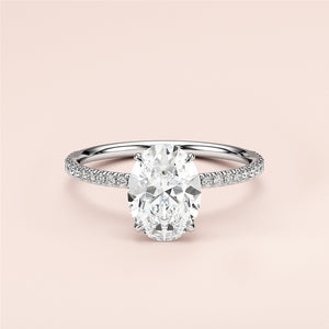 Elegant oval-shaped diamond engagement ring in 14K or 18K gold, featuring a delicate pave band against a soft background.