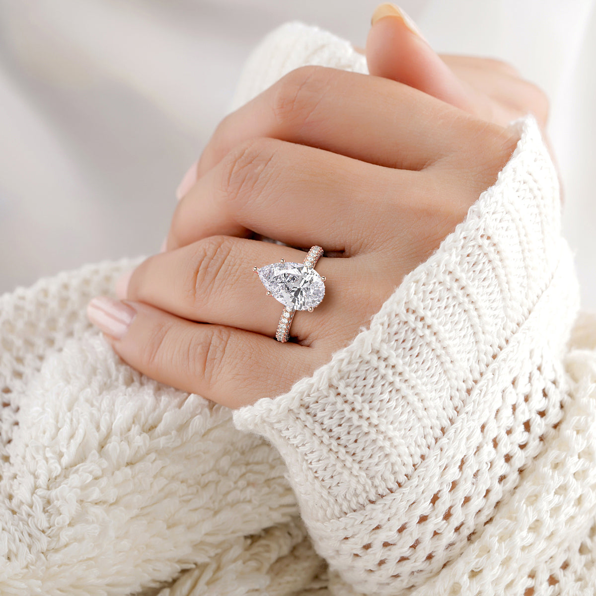 Elegant pear-shaped diamond ring in 14K rose gold, featuring hidden halo accents and prongs, worn on a model's hand.