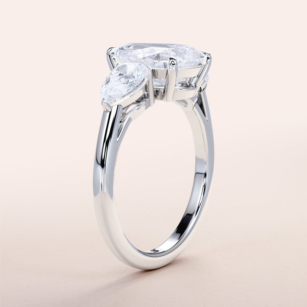 Elegant 14K or 18K white gold engagement ring with an oval-cut diamond center and pear side stones, perfect for any occasion.