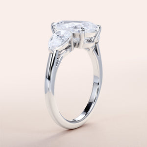 Elegant 14K or 18K white gold engagement ring with an oval-cut diamond center and pear side stones, perfect for any occasion.