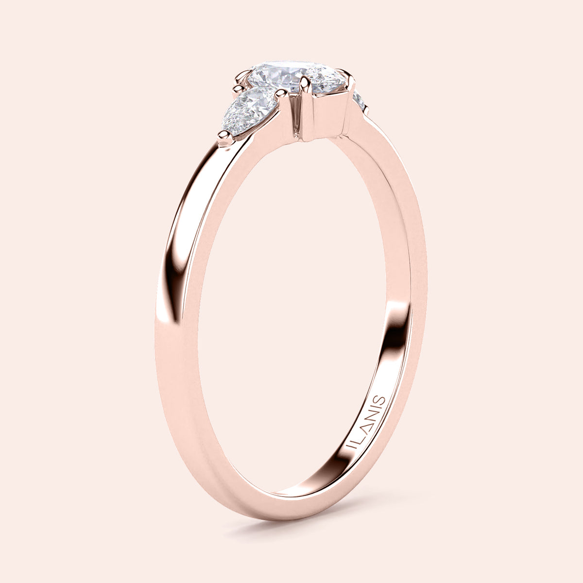 Elegant 14K or 18K rose gold engagement ring with three stone pear-cut diamonds, displayed on a soft beige background.