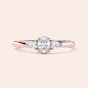 Elegant 14K rose gold engagement ring featuring an oval diamond and pear-shaped side stones, perfect for a timeless look.