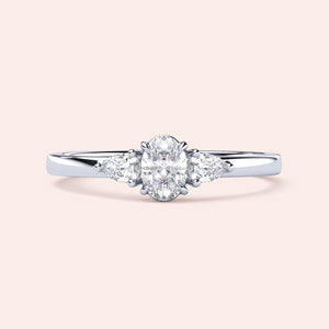Elegant 14K white gold engagement ring featuring an oval diamond center and two pear-shaped side stones in a three-stone setting.