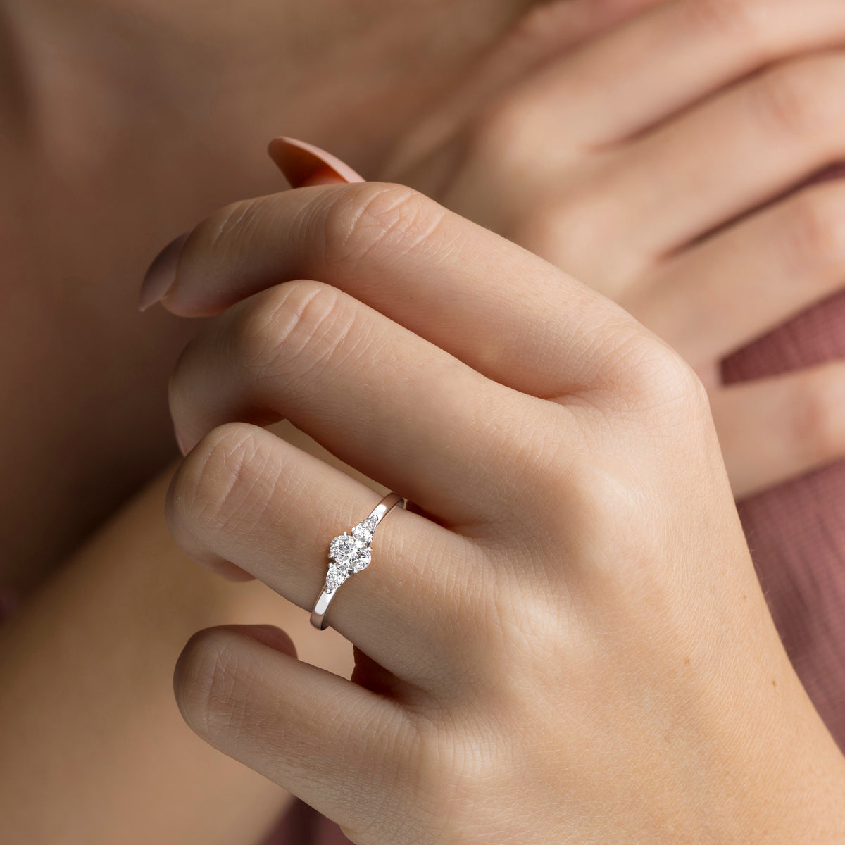 Woman wearing a stunning 14K white gold engagement ring with a sparkling pear-shaped diamond and delicate side stones.