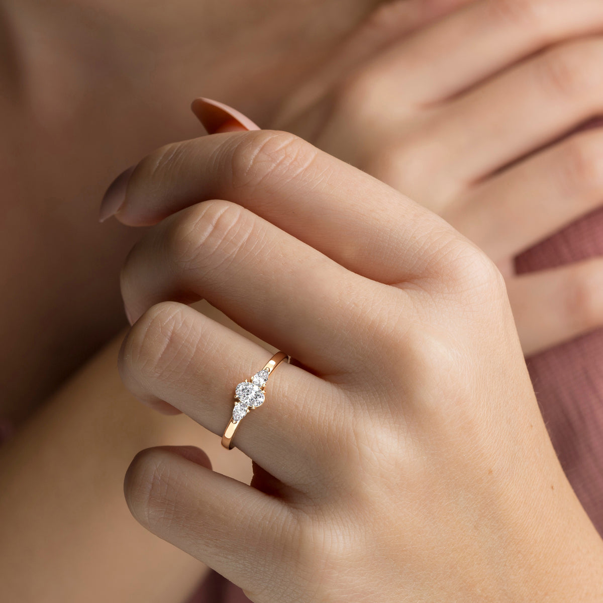 Elegant 14K yellow gold three-stone engagement ring with pear side stones, worn on model's hand for a stunning look.