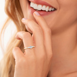Woman wearing a 14K yellow gold Rhys oval three-stone ring with side pear diamonds, sparkling beautifully on her hand.