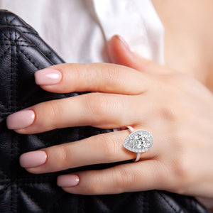 Pear-shaped diamond ring set in 14K white gold, worn on model's finger, showcasing its elegance and fine craftsmanship.