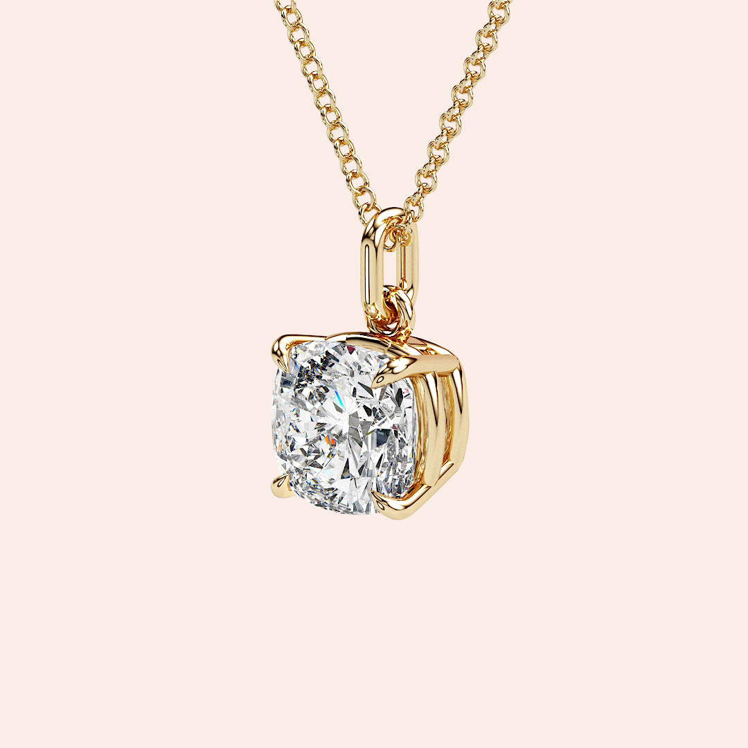 A detailed close-up of a cushion-cut solitaire diamond pendant set in a four-prong yellow gold basket. The refined craftsmanship highlights the brilliance of the diamond, making it a must-have piece for any fine jewelry collection.| #14KRecycledYellowGold #18KRecycledYellowGold